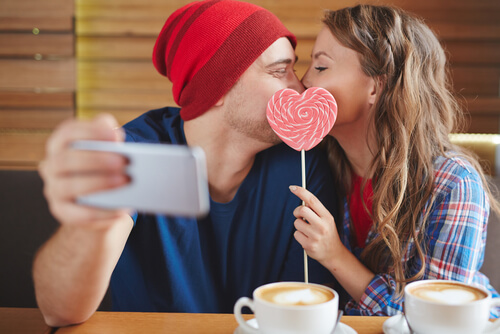 ハートのぺろぺろキャンディーを口にあてキスするカップル