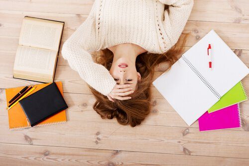 ノートや本に囲まれ、ストレスを感じる女性