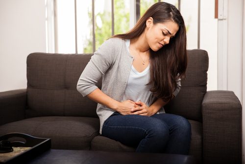 おなかをおさえて痛みに耐える女性