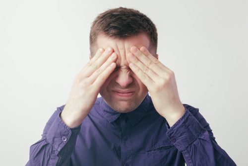 目をつぶり額に手をやる男性