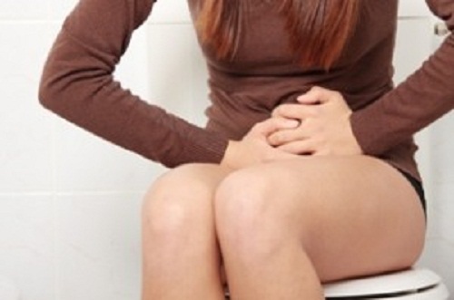 トイレでお腹を押さえる女性