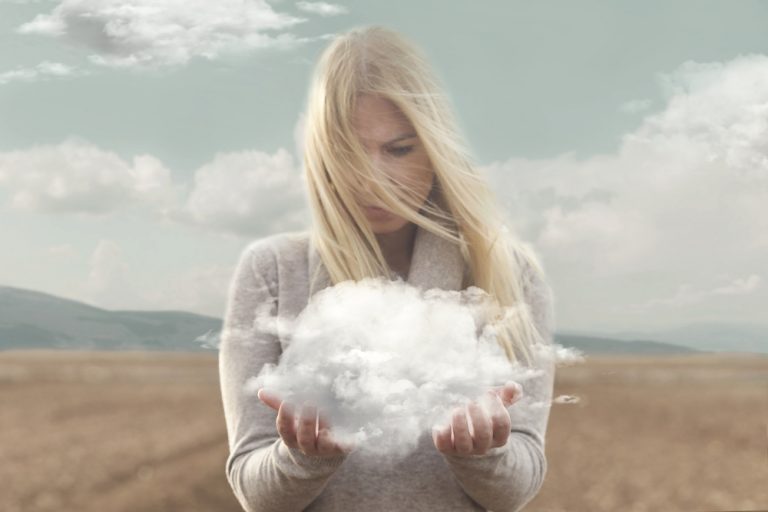 両手の雲を見つめる女性