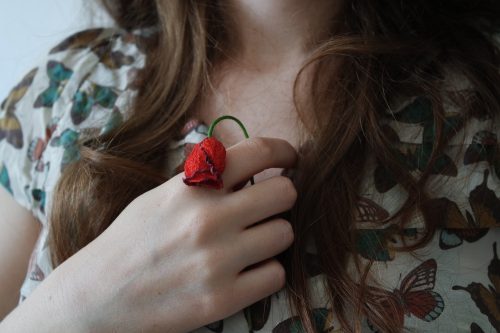 赤い花を胸にあてた女性