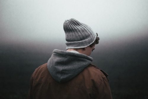 背を向けて立つ毛糸帽の男性