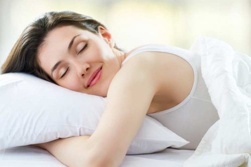 枕を抱いてほほ笑み眠る女性