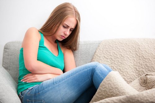 ソファでお腹を抑える女性