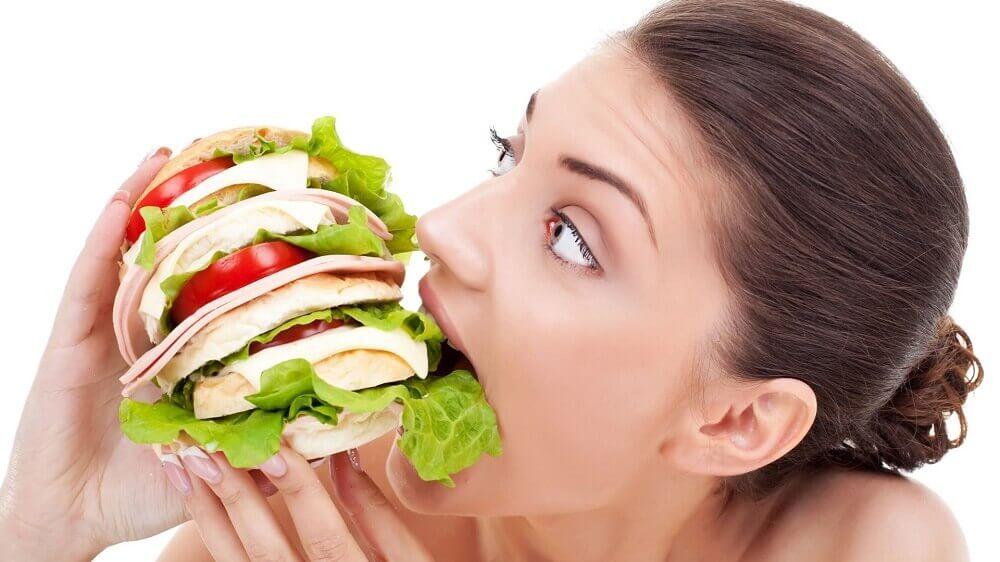 大きなサンドイッチを食べる女性