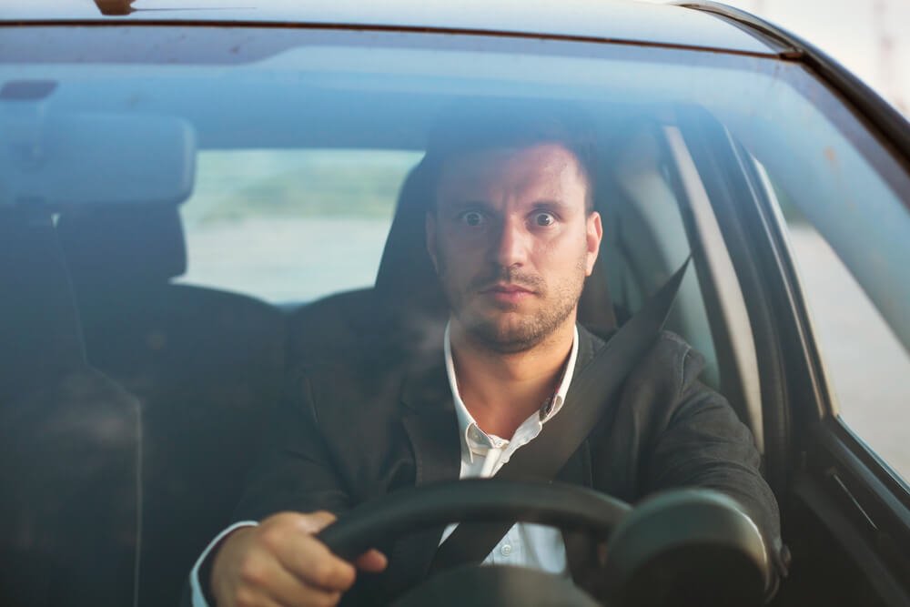 目を見開いて運転する男性
