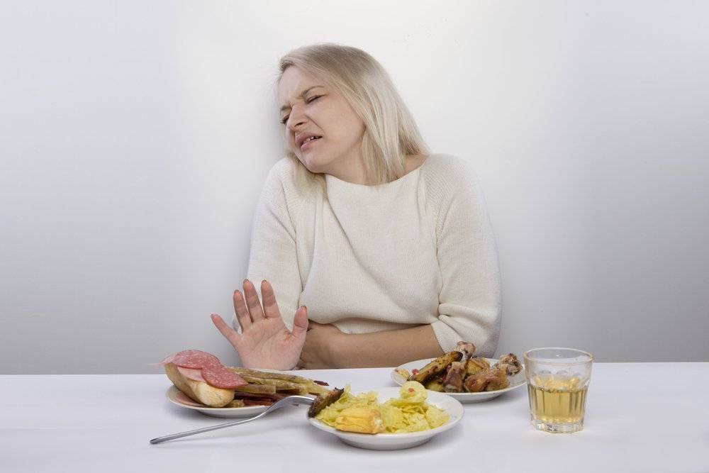 重い食事を前に顔をしかめる女性