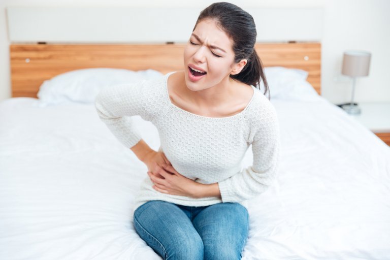 ベッドで右脇腹が痛む女性