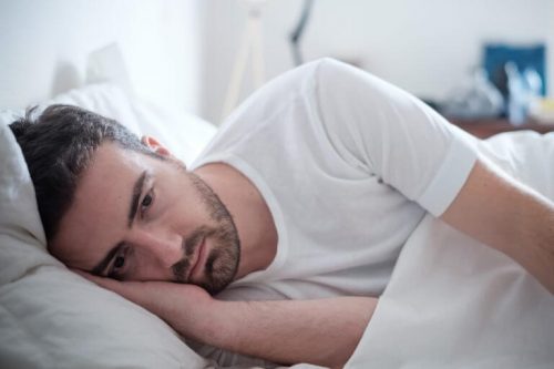 ベッドに横たわり目を開けている男性