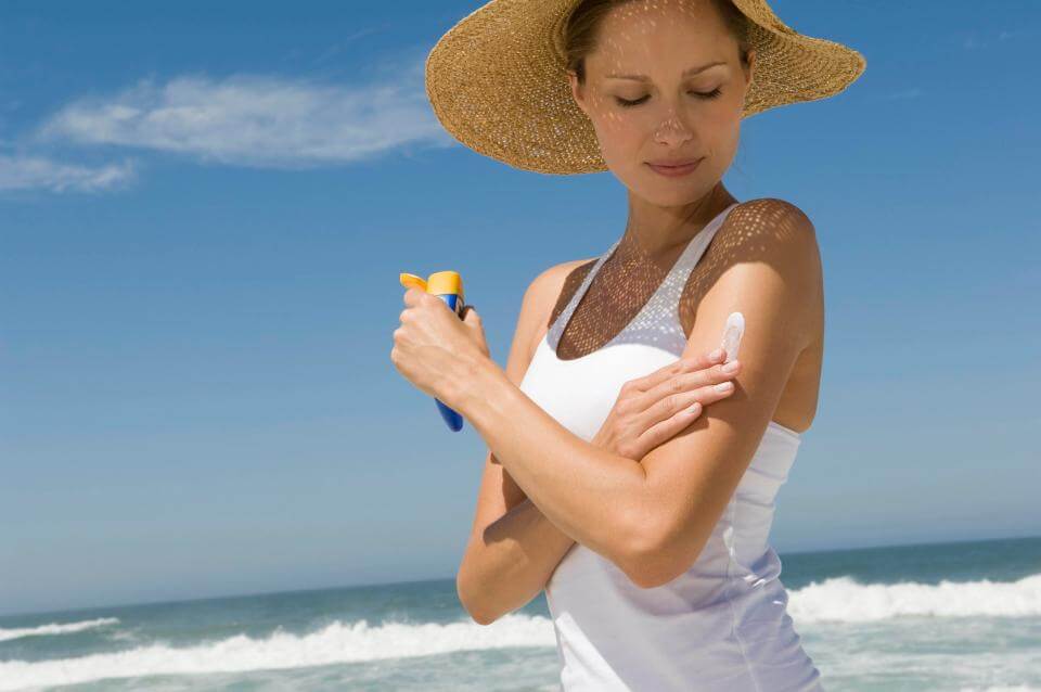 海で日焼け止め剤を塗る女性