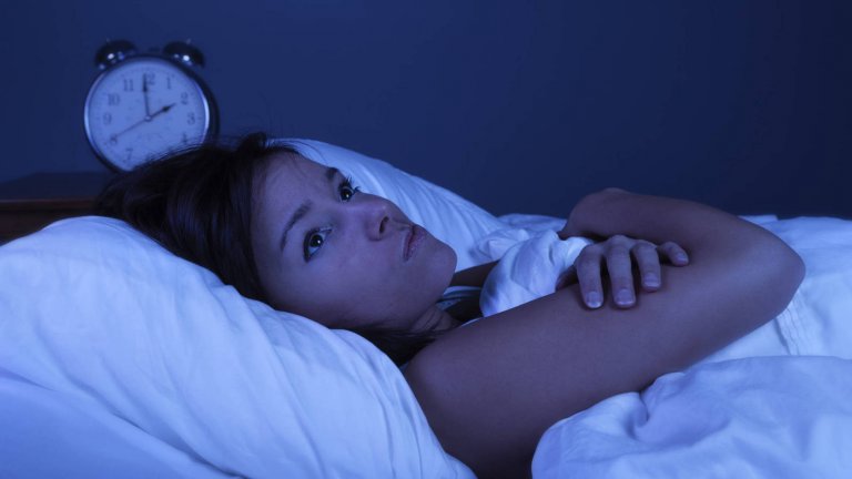 ベッドで眠れず目を開けている女性