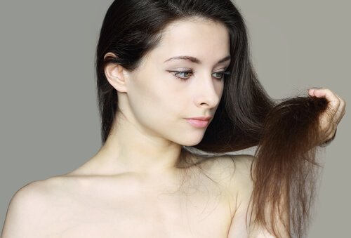 自分の髪の毛先を見つめる女性