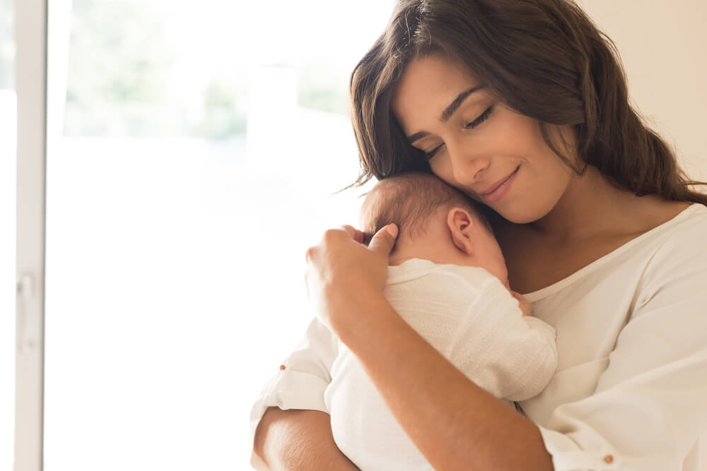 赤ちゃんを抱き目を閉じる女性