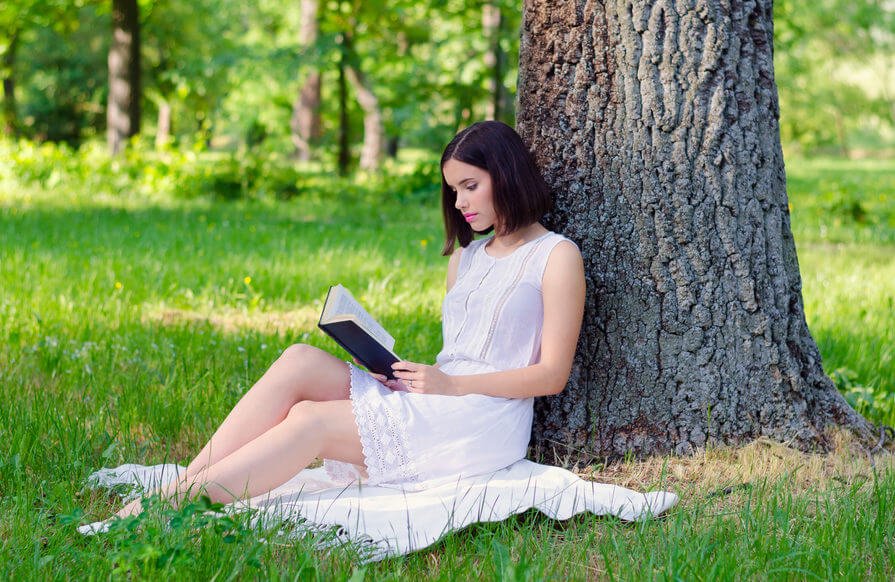木の下で読書をする女性