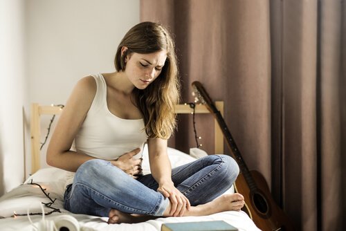 ベッドで腹部を抑える女性
