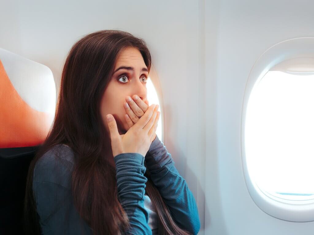 飛行機で口を抑える女性　吐き気を抑える