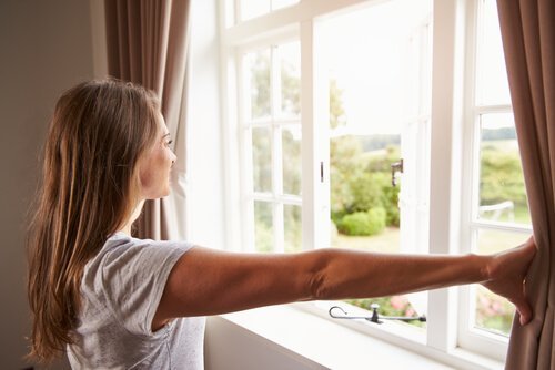 窓を開ける女性 カビを除去する