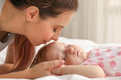 眠っている赤ちゃんを見守る母親