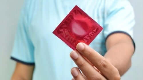 マイコプラズマ・ジェニタリウム：原因、症状、治療  　コンドームを持つ男性
