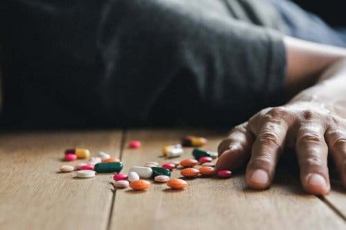 薬と床に倒れる男性 薬物中毒